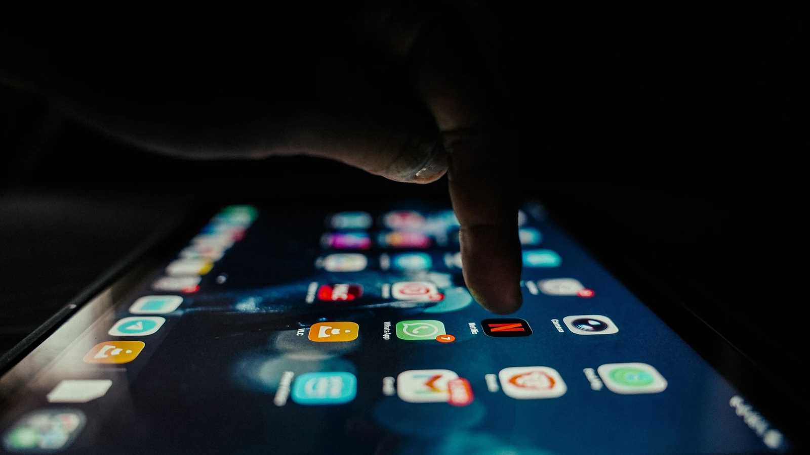 Latest porn stats: a hand tapping app icons on a smartphone screen in the dark